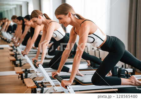Doing push ups on the special device. Women in fitness center are doing exercises Doing push ups on the special device. Women in fitness center are doing exercises 128565480