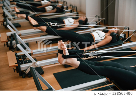 Legs stretching. Women in fitness center are doing exercises Legs stretching. Women in fitness center are doing exercises 128565490