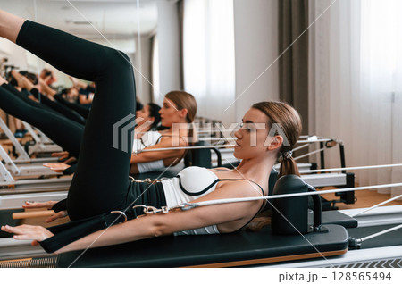 Side view. Stretching the legs. Women in fitness center are doing exercises 128565494