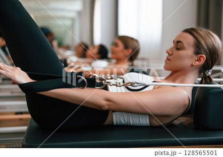 Against the mirror. Women in fitness center are doing exercises 128565501