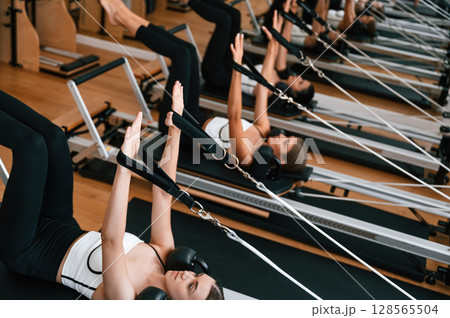 Lying down in a row and doing stretches. Women in fitness center are doing exercises 128565504