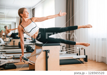 On the leg. Young woman in fitness center is doing exercises On the leg. Young woman in fitness center is doing exercises 128565520