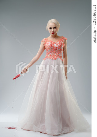 Bride in a blood-stained gown poses dramatically in studio setting 128566211