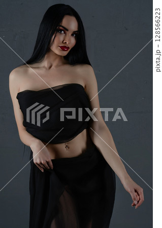 Elegant woman showcasing beauty in lingerie and sheer fabric indoors 128566223