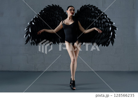 Elegant woman in lingerie exuding beauty with striking black wings in a studio Elegant woman in lingerie exuding beauty with striking black wings in a studio 128566235