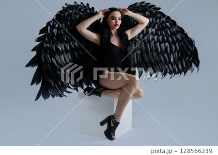 Elegance and allure of a woman in lingerie with striking black wings Elegance and allure of a woman in lingerie with striking black wings 128566239