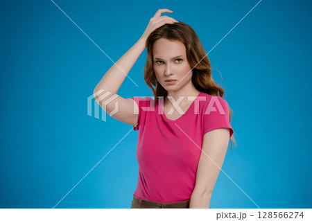 Woman posing in a studio setting expressing various emotions against a vibrant blue background Woman posing in a studio setting expressing various emotions against a vibrant blue background 128566274