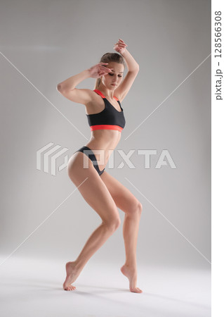 Woman poses dynamically in sport attire during a studio photoshoot session Woman poses dynamically in sport attire during a studio photoshoot session 128566308