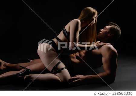 Intimate moment between a couple in stylish lingerie captured in a dark setting Intimate moment between a couple in stylish lingerie captured in a dark setting 128566330