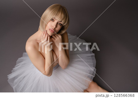 Elegant woman modeling in lingerie with a tulle skirt against a neutral backdrop Elegant woman modeling in lingerie with a tulle skirt against a neutral backdrop 128566368