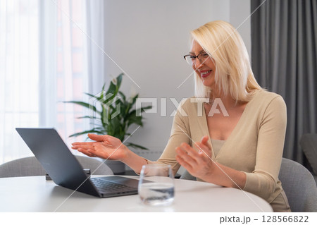 Beige dressed female psychologist giving online consultation on notebook. Relaxed blonde therapist talking to client via video call. Online mental health support in bright and comfortable room. Beige dressed female psychologist giving online consultation on notebook. Relaxed blonde therapist talking to client via video call. Online mental health support in bright and comfortable room. 128566822