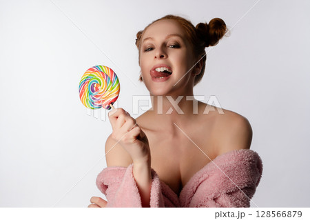 Beautiful woman in lingerie playfully enjoying a large lollipop indoors Beautiful woman in lingerie playfully enjoying a large lollipop indoors 128566879