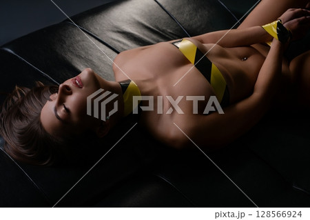 Woman reclining on a couch, showcasing beauty and elegance in a bold setting Woman reclining on a couch, showcasing beauty and elegance in a bold setting 128566924