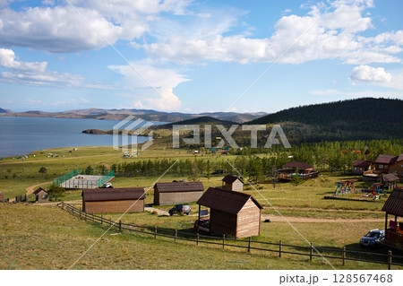Beautiful wooden houses dot the landscape overlooking a calm lake Beautiful wooden houses dot the landscape overlooking a calm lake 128567468