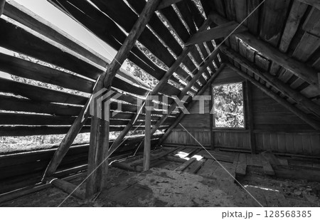 Abandones interior view of a wooden structure showcasing exposed beams 128568385