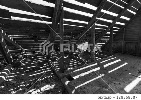 Dark interior view with wooden structure showcasing exposed beams Dark interior view with wooden structure showcasing exposed beams 128568387