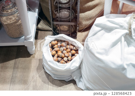 Burlap white bag of hazel nuts on wooden floor, top view Burlap white bag of hazel nuts on wooden floor, top view 128568423