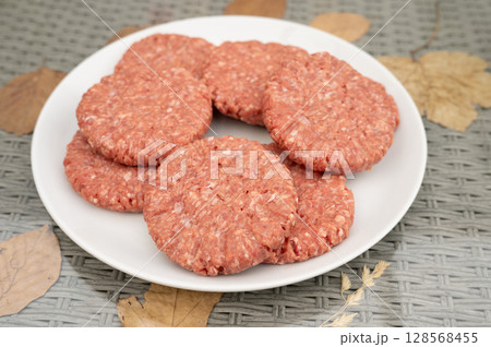 Raw beef patties on white plate with autumn leaves background. National Mincemeat Day 128568455