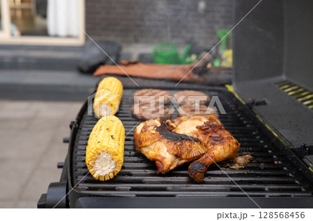 Grilled chicken and corn with burgers on backyard barbecue grill Grilled chicken and corn with burgers on backyard barbecue grill 128568456