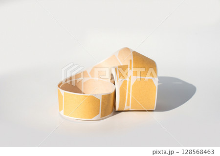 Curved roll of blank yellow adhesive labels on white background 128568463