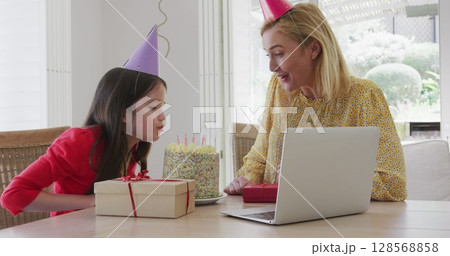 Image of balloons over happy mother and daughter with cake making birthday laptop image call 128568858