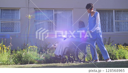 Image of light moving over female nurse pushing senior man in wheelchair Image of light moving over female nurse pushing senior man in wheelchair 128568965