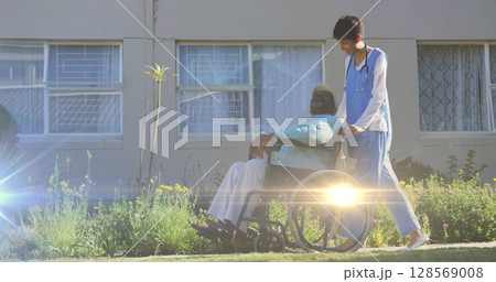 Image of light moving over nurse pushing senior man in wheelchair 128569008