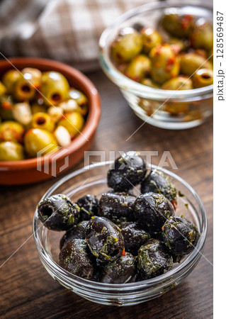 Tapas. Flavored pickled olives in bowl on wooden table. 128569487
