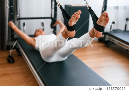 Young woman in fitness center is doing exercises 128570053