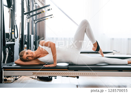 Lying down on the side. Young woman in fitness center is doing exercises 128570055