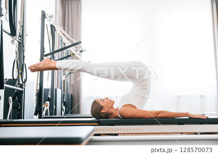 Legs are up. Young woman in fitness center is doing exercises 128570073