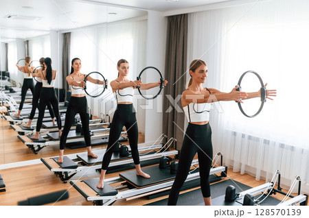 Three women in fitness center are doing exercises 128570139