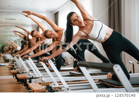 They lean to the side, do back stretches. Women in fitness center are doing exercises They lean to the side, do back stretches. Women in fitness center are doing exercises 128570140