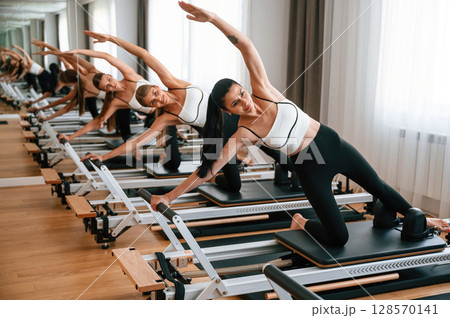 They lean to the side, do back stretches. Women in fitness center are doing exercises They lean to the side, do back stretches. Women in fitness center are doing exercises 128570141