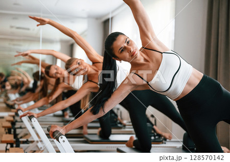 They lean to the side, do back stretches. Women in fitness center are doing exercises They lean to the side, do back stretches. Women in fitness center are doing exercises 128570142