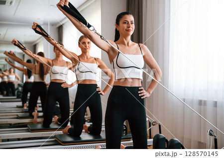 Three women in fitness center are doing exercises Three women in fitness center are doing exercises 128570145