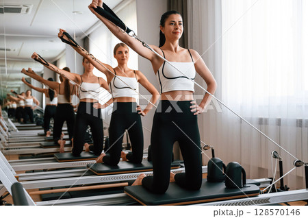 Against the mirror. Women in fitness center are doing exercises 128570146