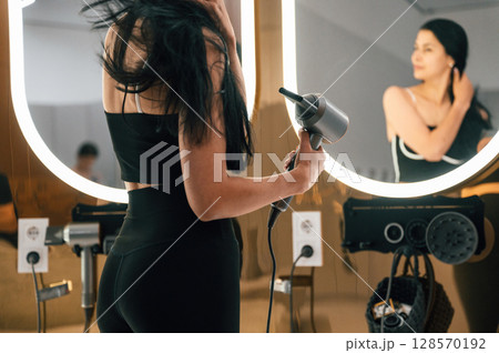 Woman is drying her hair in the changing room Woman is drying her hair in the changing room 128570192