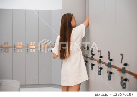 Woman is in the gym changing room with lockers Woman is in the gym changing room with lockers 128570197