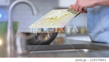 Image of light over midsection of man cooking using knife and chopping board in kitchen Image of light over midsection of man cooking using knife and chopping board in kitchen 128570601