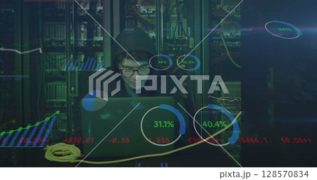 Image of data processing over asian male hacker in hoodie with laptop by computer servers 128570834