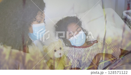 Image of grass over biracial mother with face masks and her daughter lying in hospital 128571122