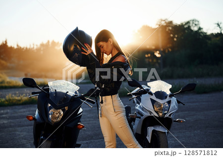 Wearing the protective helmet. Woman is with motorcycle outdoors Wearing the protective helmet. Woman is with motorcycle outdoors 128571812
