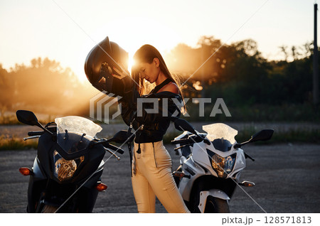 Wearing the protective helmet. Woman is with motorcycle outdoors Wearing the protective helmet. Woman is with motorcycle outdoors 128571813