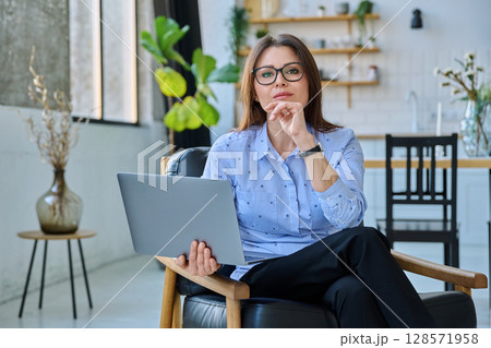 Middle aged business woman sitting in chair with laptop computer 128571958