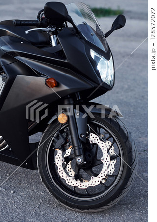 Black colored vehicle. Close up view of modern motorcycle that is parked outdoors 128572072