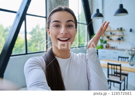 Close-up selfie portrait of teenage female looking at web camera 128572081