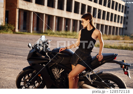 Building behind. Woman is with motorcycle outdoors 128572118