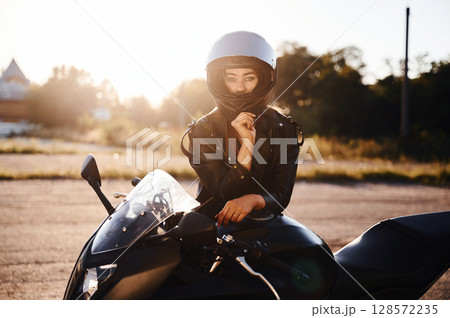 Amazing sunlight. Woman is with motorcycle outdoors 128572235