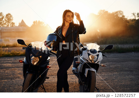 Between two vehicles, against smoke. Woman is with motorcycle outdoors 128572257